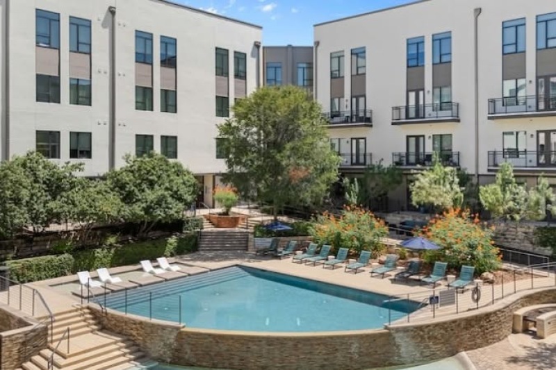 aerial view of the swimming pool, lounge chairs, and apartment balconies at river house apartments in downtown san antonio