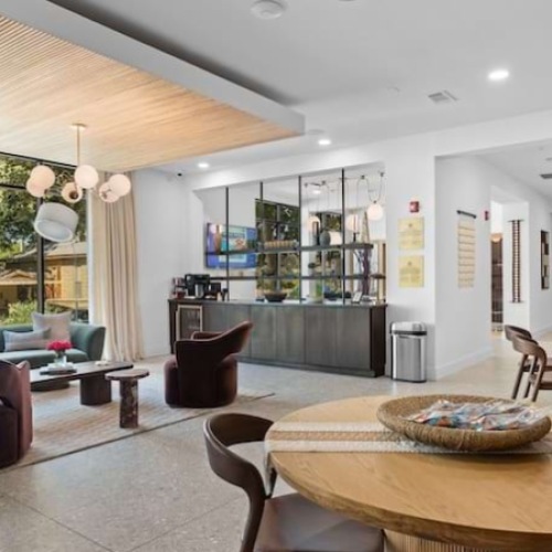 Bright clubhouse social lounge with dining table and lounge seating at River House luxury apartments on the San Antonio River Walk, steps from The Pearl