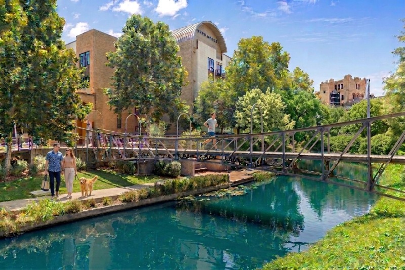 a group of people walking on a bridge over a pond